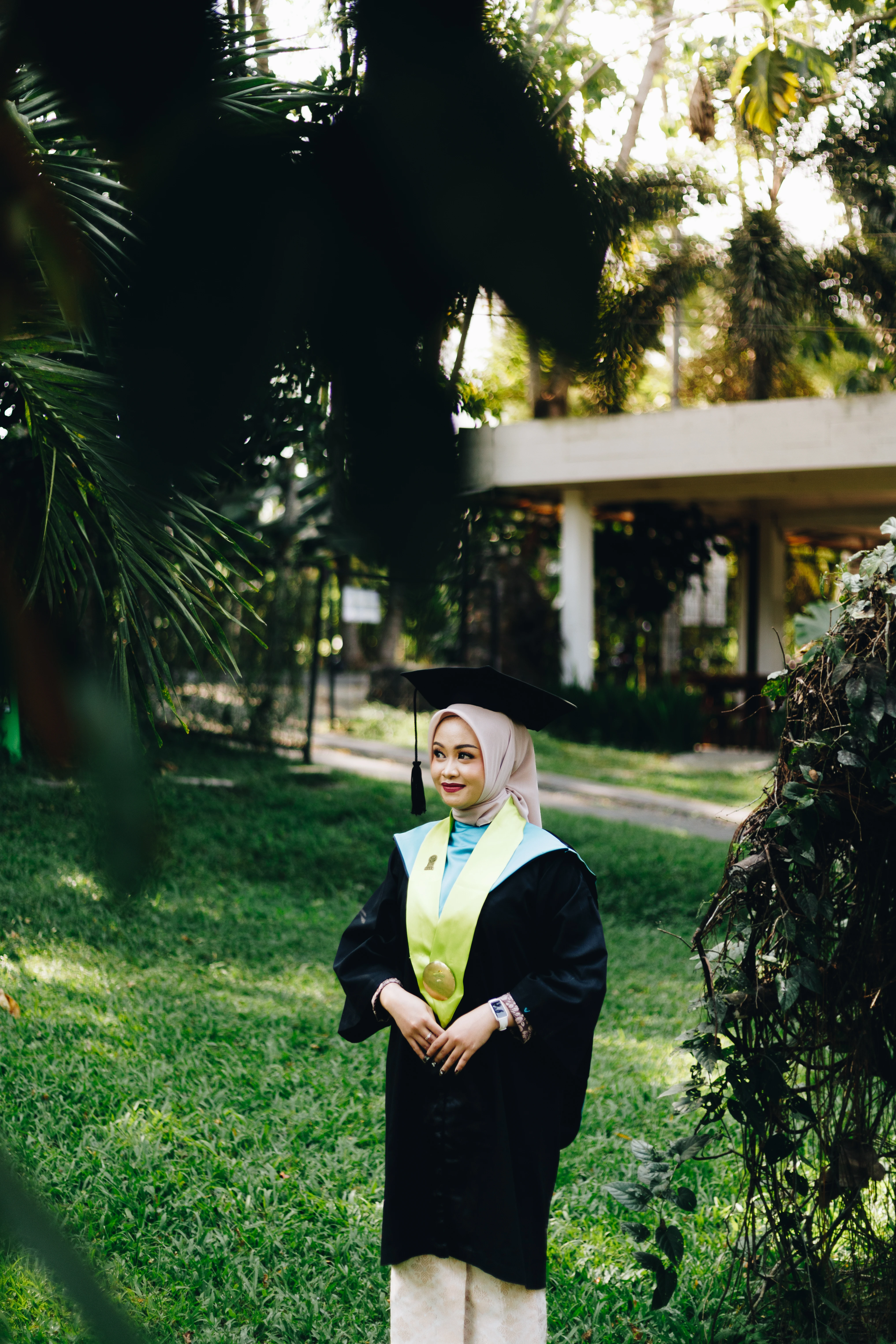 Dokumentasi wisuda outdoor mahasiswa UNY mengenakan toga lengkap dengan latar pepohonan rindang kampus Karangmalang Jogja - Toga & Co.