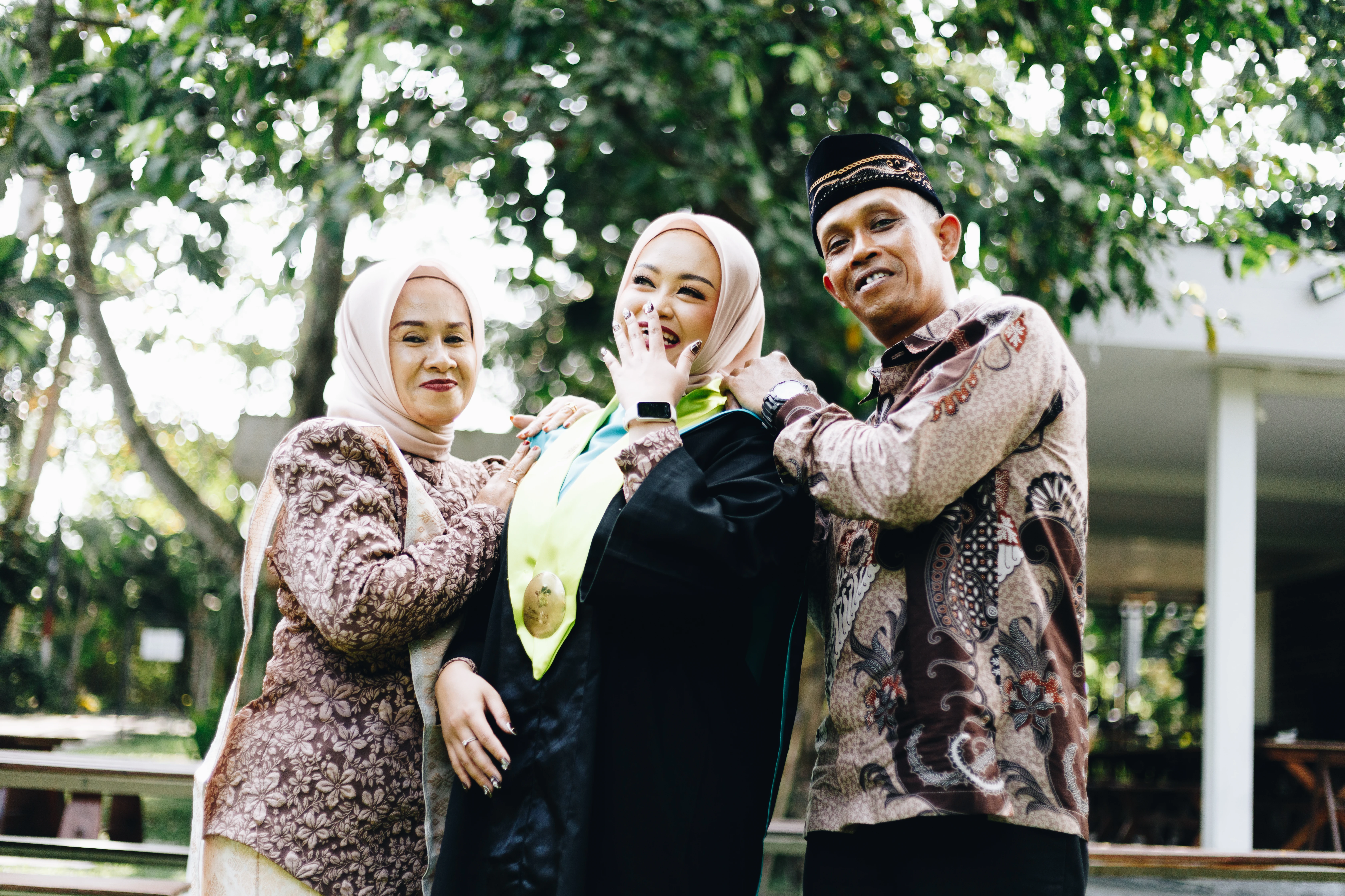 Foto wisuda landscape bersama sahabat dan keluarga di ruang terbuka hijau Yogyakarta bernuansa hangat - Toga & Co.