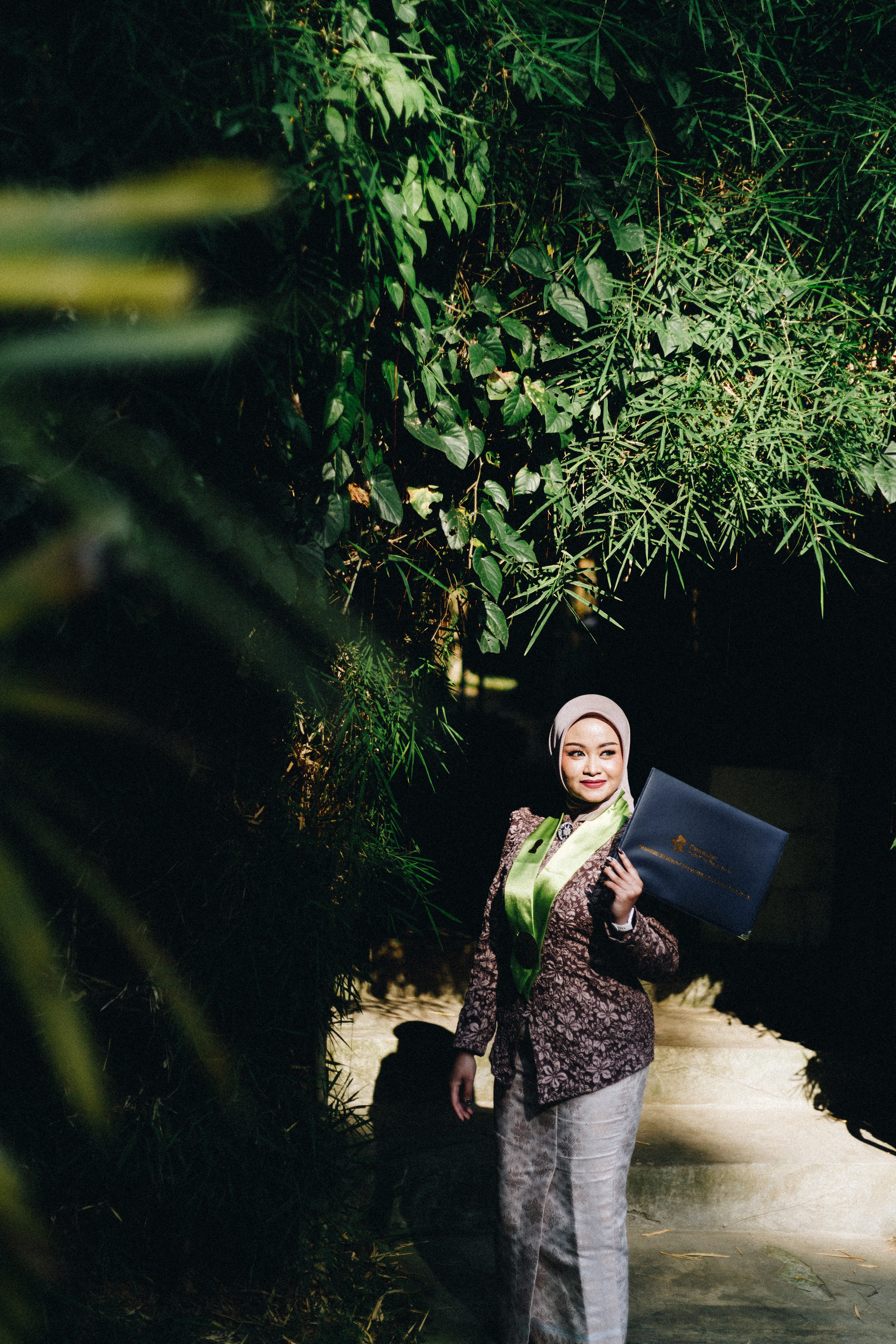 Foto wisuda outdoor estetik di kawasan asri Yogyakarta dengan gradasi warna tanah dan dedaunan - Toga & Co.